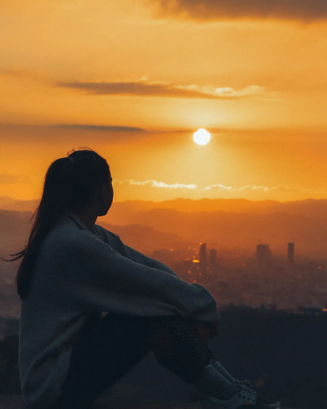 Persona di spalle guarda un panorama al tramonto durante un viaggio per ritrovare se stessi.
